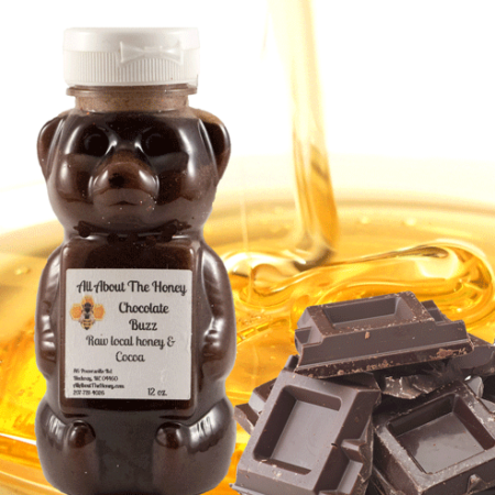 A bear shaped honey bottle sitting on top of chocolate.